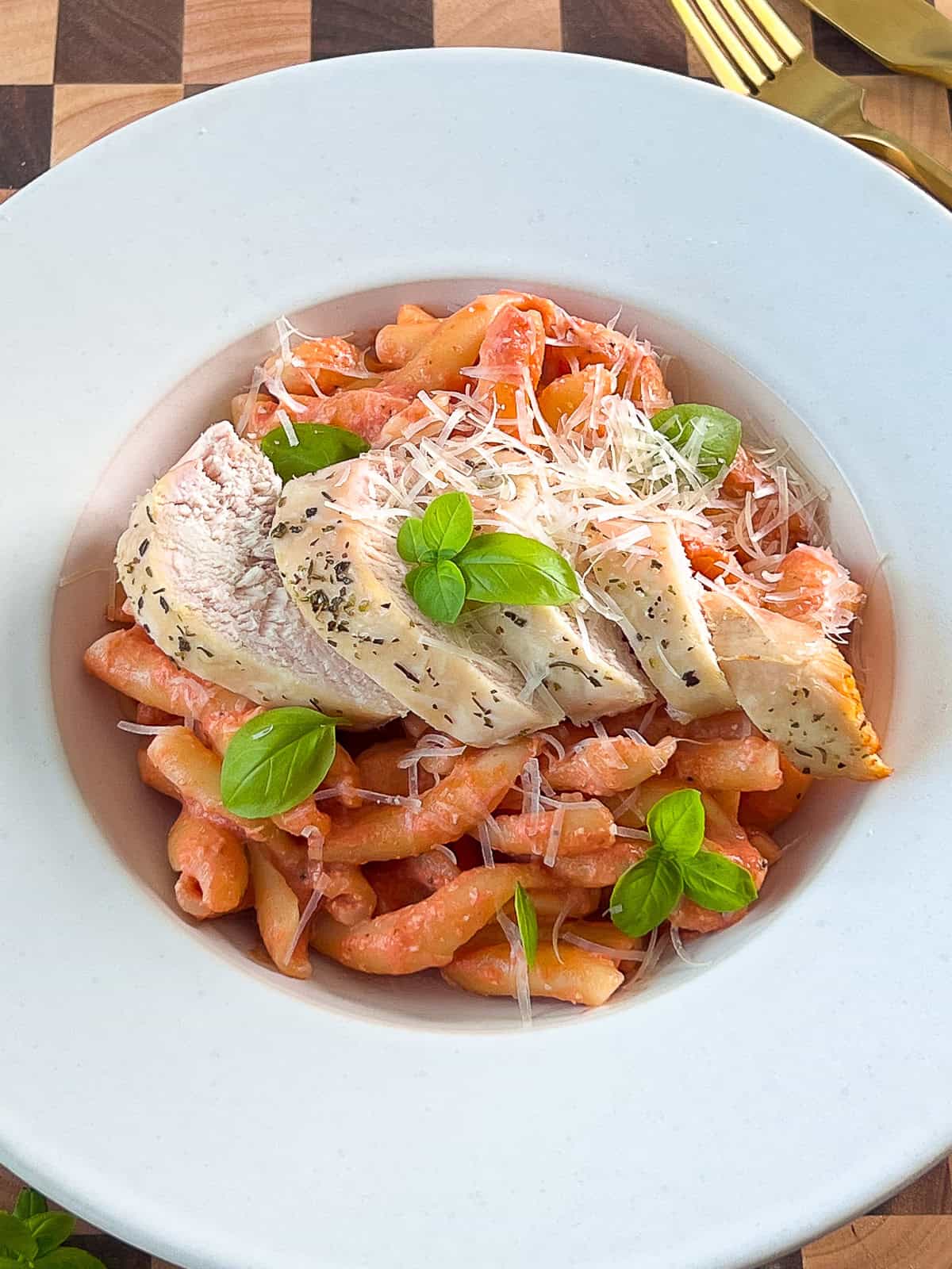 Sliced chicken breast served on pasta with creamy tomato mozzarella sauce