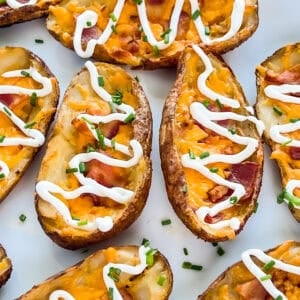 Smoked potato skins with bacon, cheddar cheese, and sour cream on a serving platter