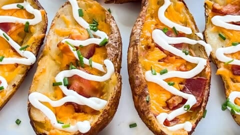 Smoked potato skins with bacon, cheddar cheese, and sour cream on a serving platter