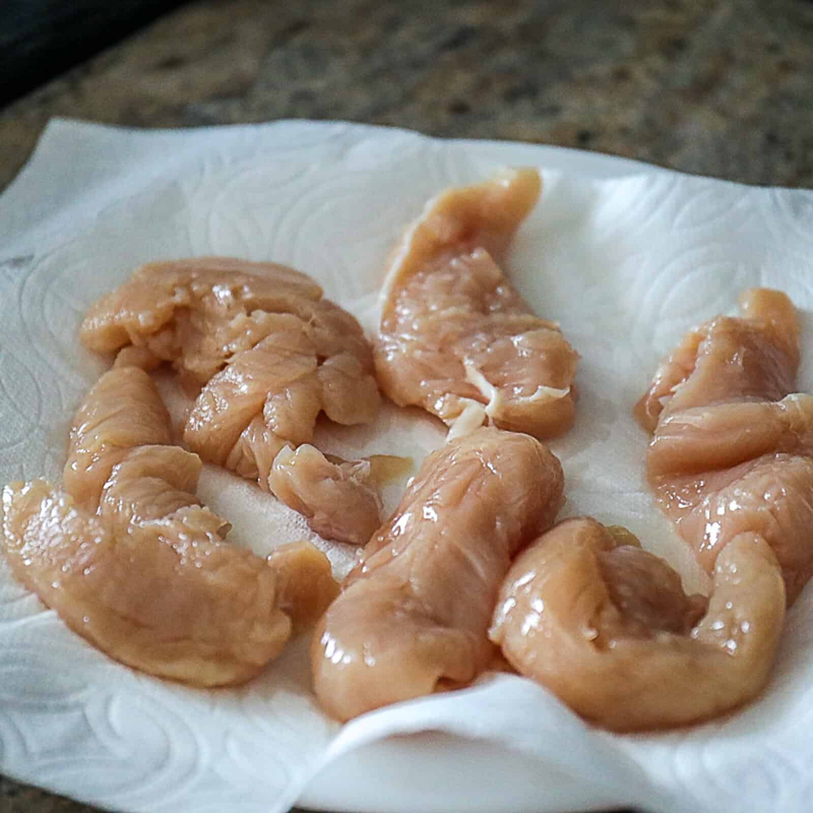 Raw chicken tenderloins seasoned with salt and pepper on a plate
