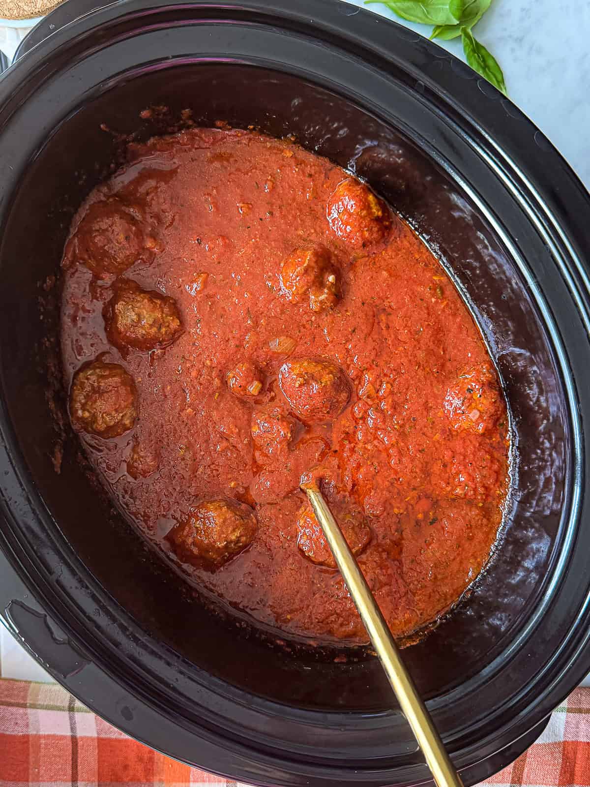 Slow cooker filled with meatballs simmering in tomato sauce