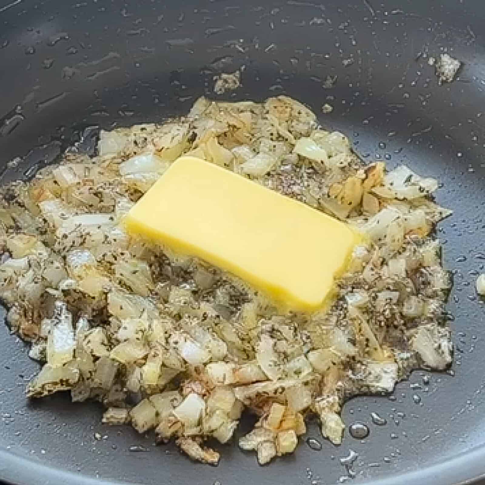 Cooking diced onion with garlic and Italian seasonings in a skillet on the stove