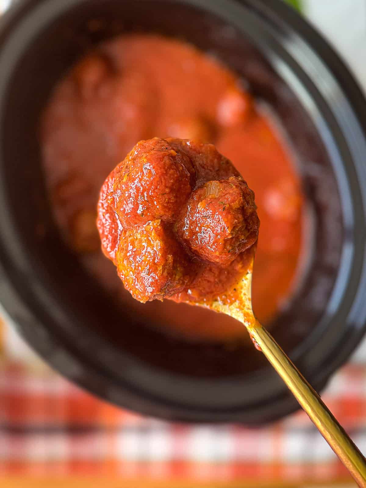 Tender homemade meatballs simmered in tomato sauce inside a slow cooker