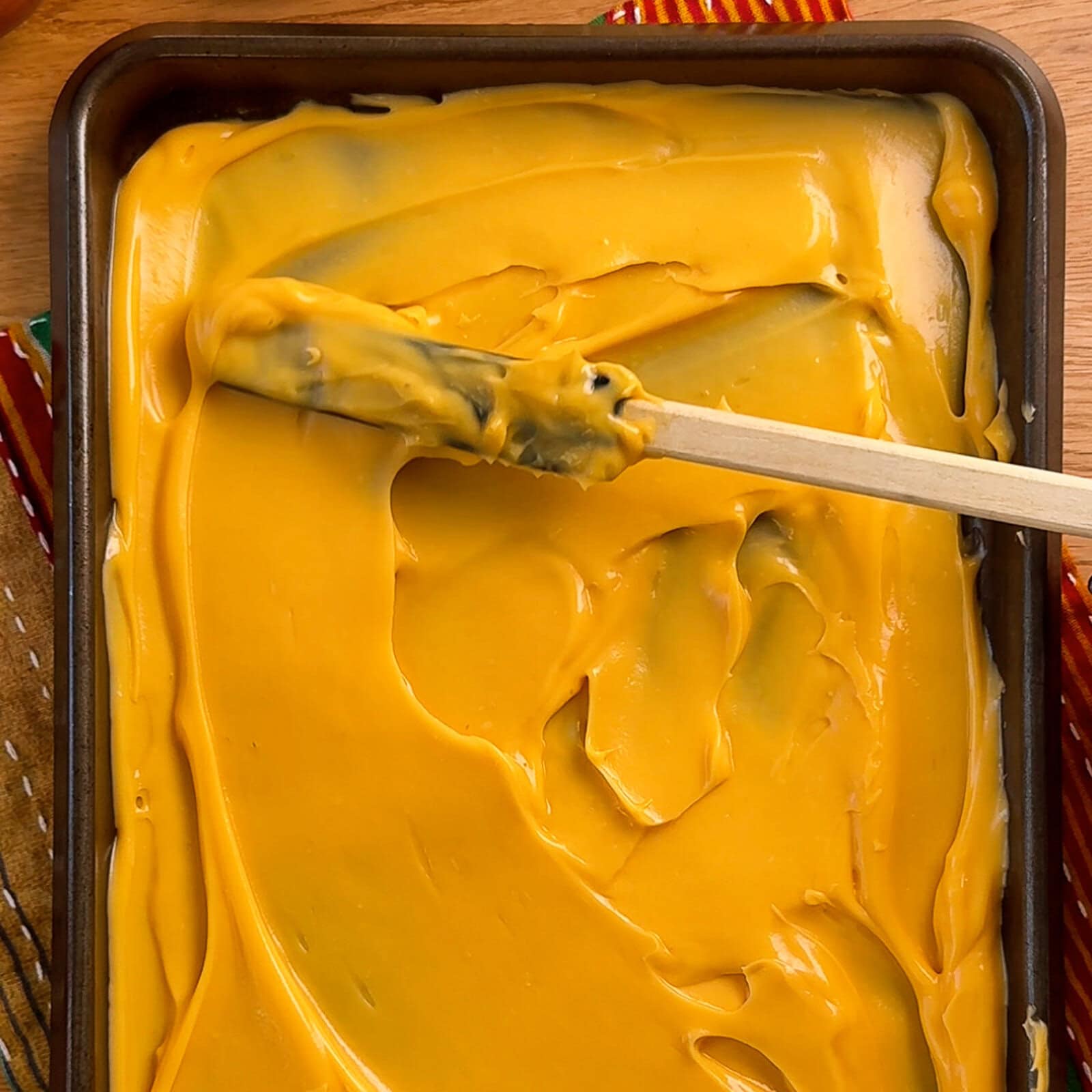 Baking tray spread with creamy nacho cheddar cheese layer