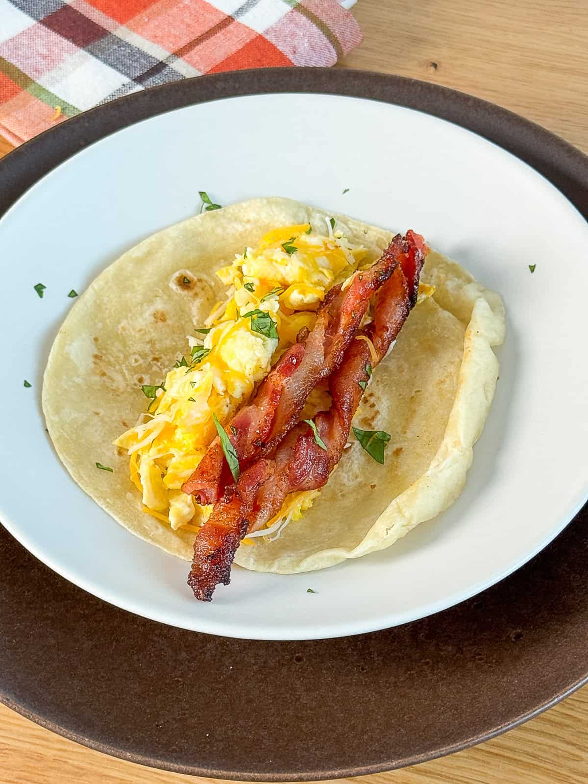 Breakfast plate with scrambled eggs and a BBQ twisted bacon taco, plated and ready to eat
