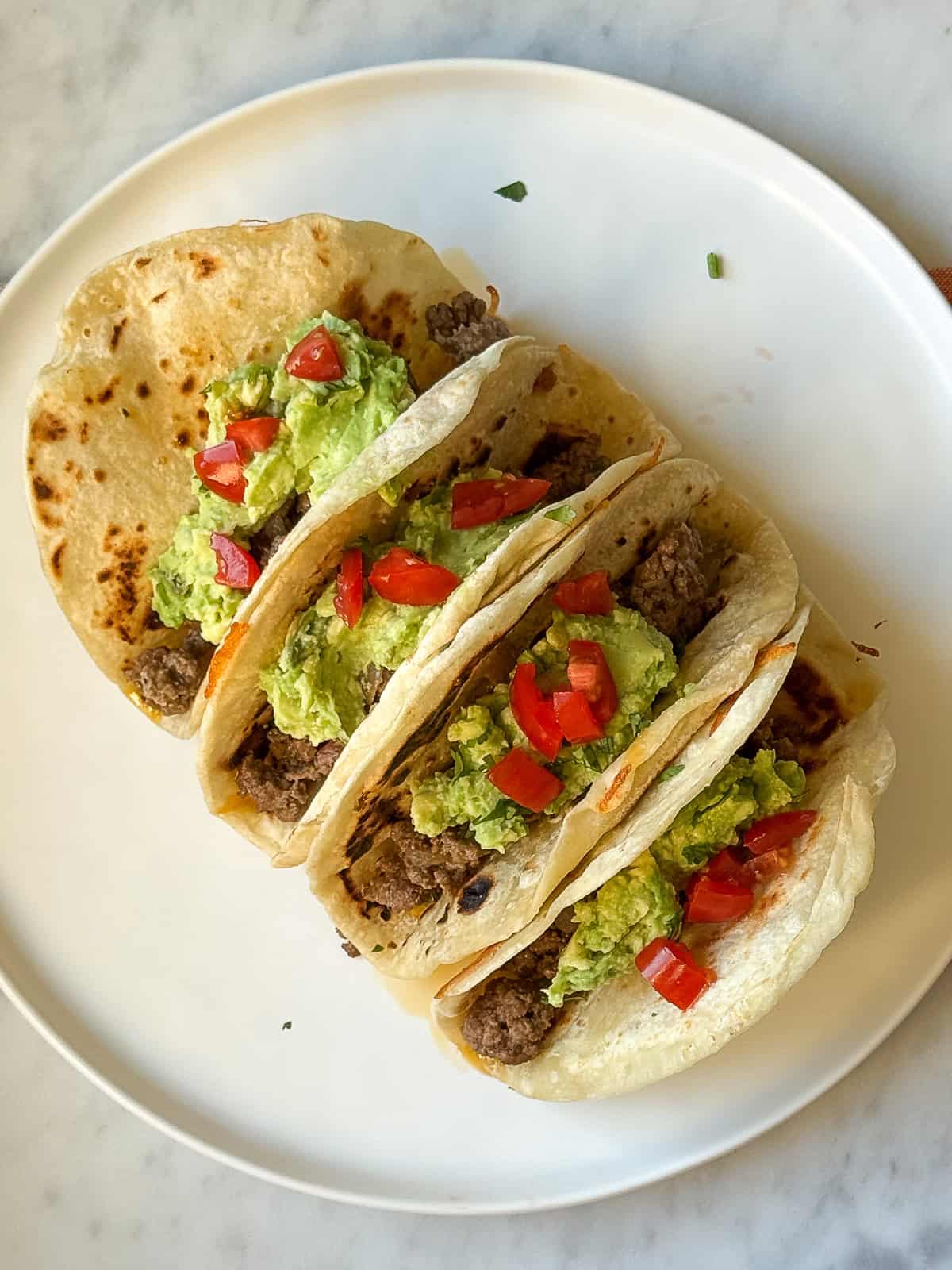 Dinner plate with Salsa Verde Ground Beef Tacos and assorted toppings