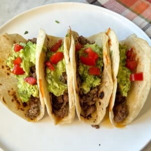 Salsa Verde Ground Beef Tacos on a plate with avocado slices and tomato wedges