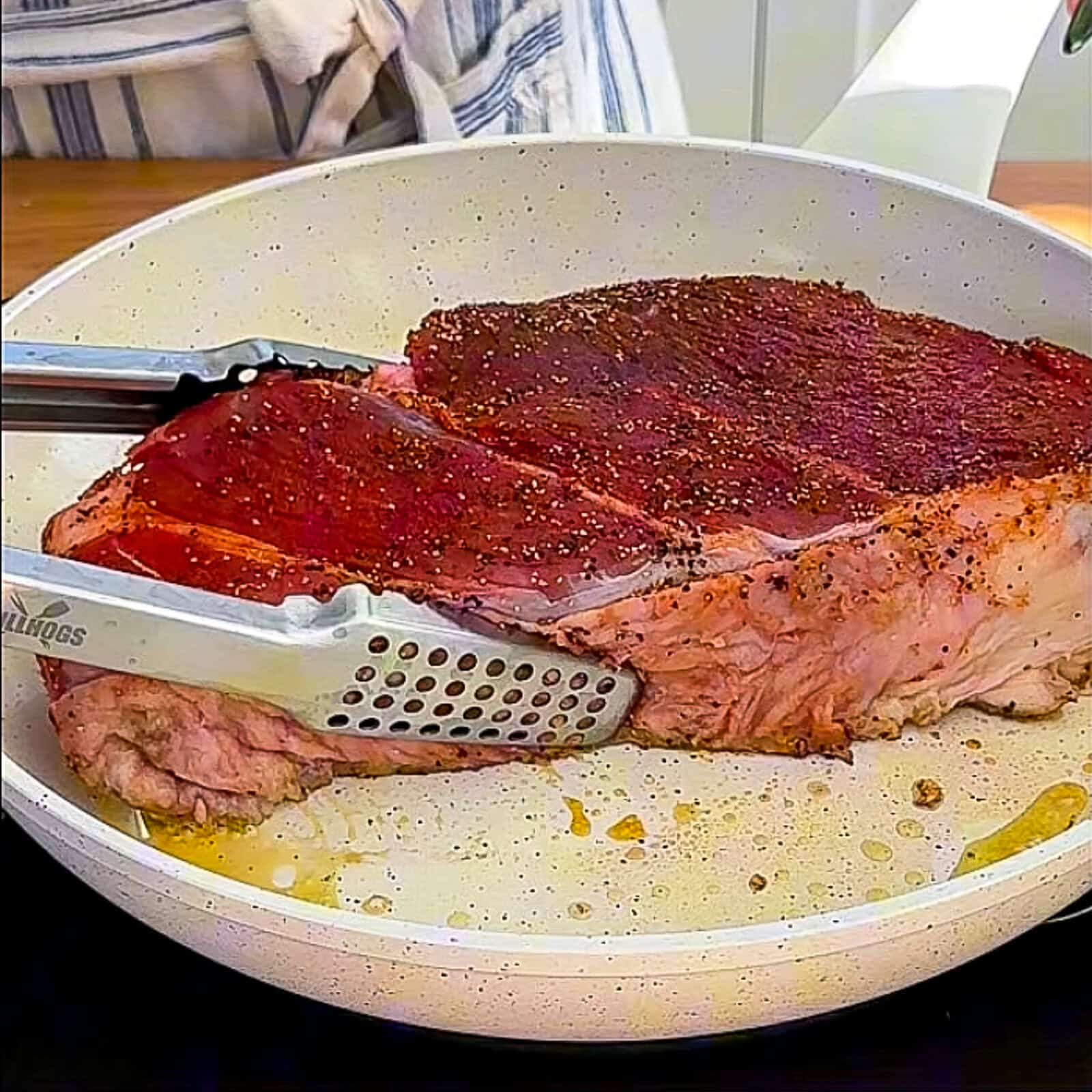 Seasoned beef chuck being seared in a hot pan