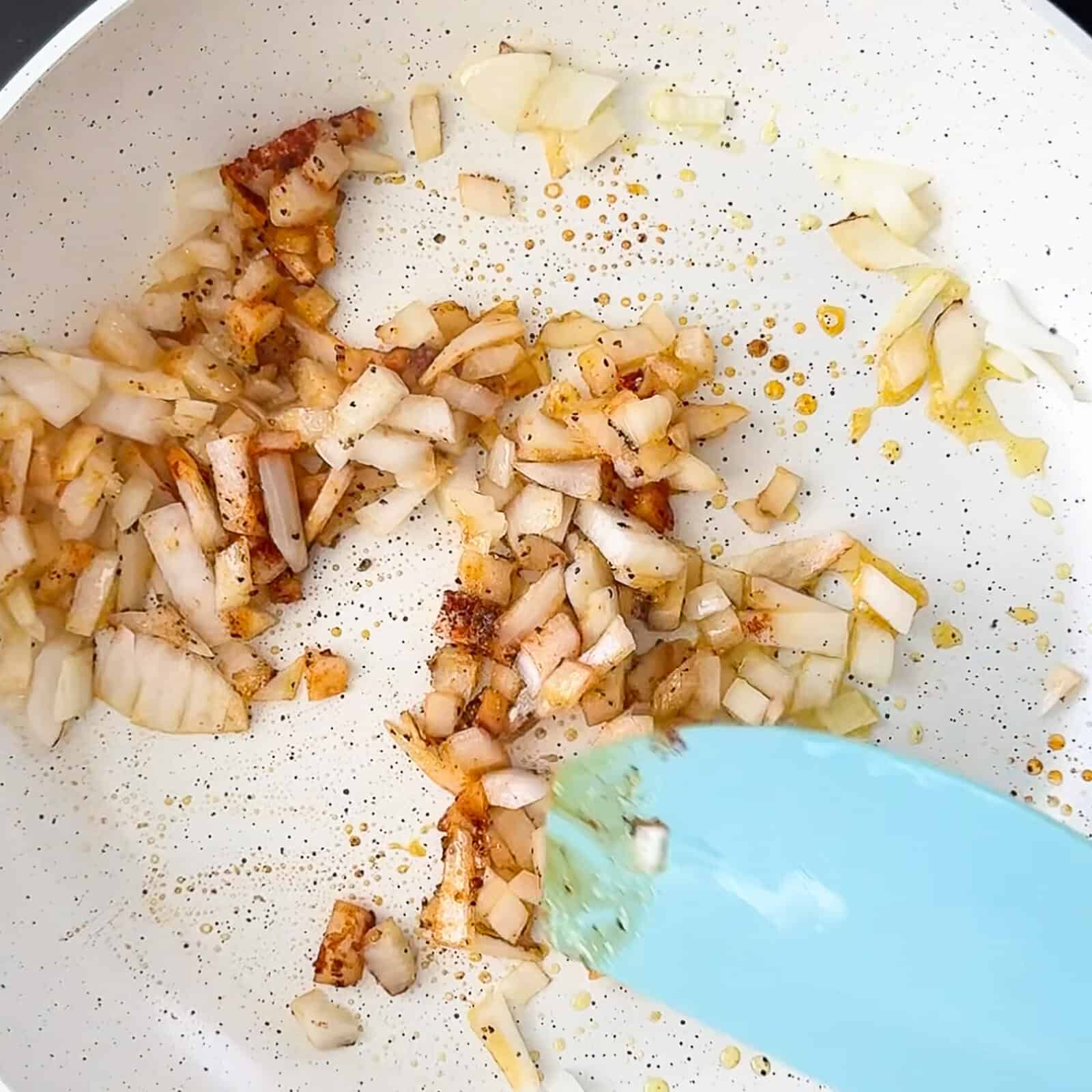 Cooking diced onions in a pan with taco seasonings