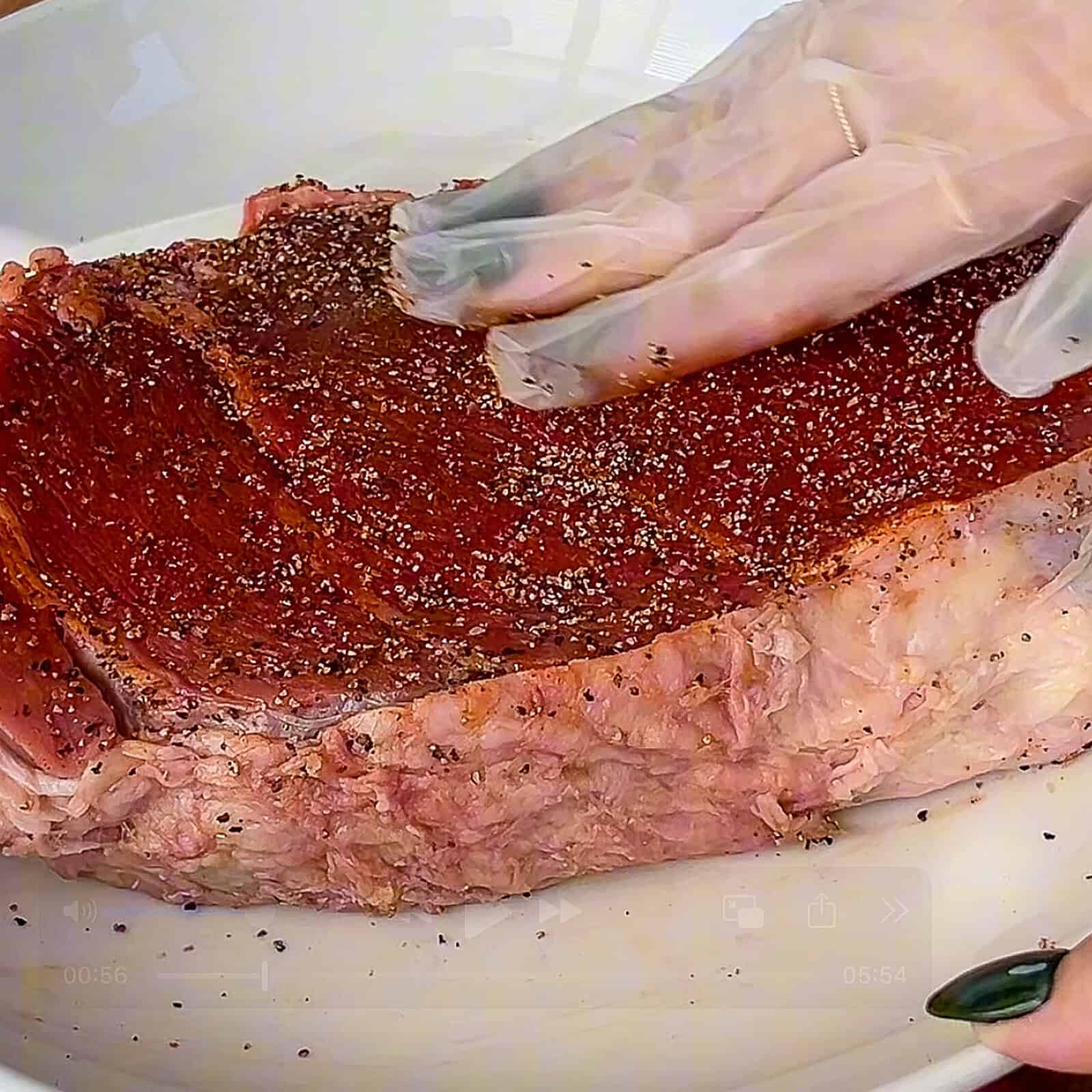 Beef chuck being seasoned with spices before searing