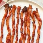 Close-up of twisted bacon in the oven recipe with text overlay showing crispy, seasoned strips