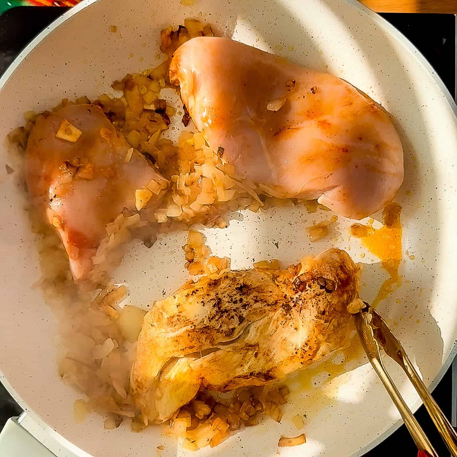 Chicken breasts browning in a pan before slow cooking