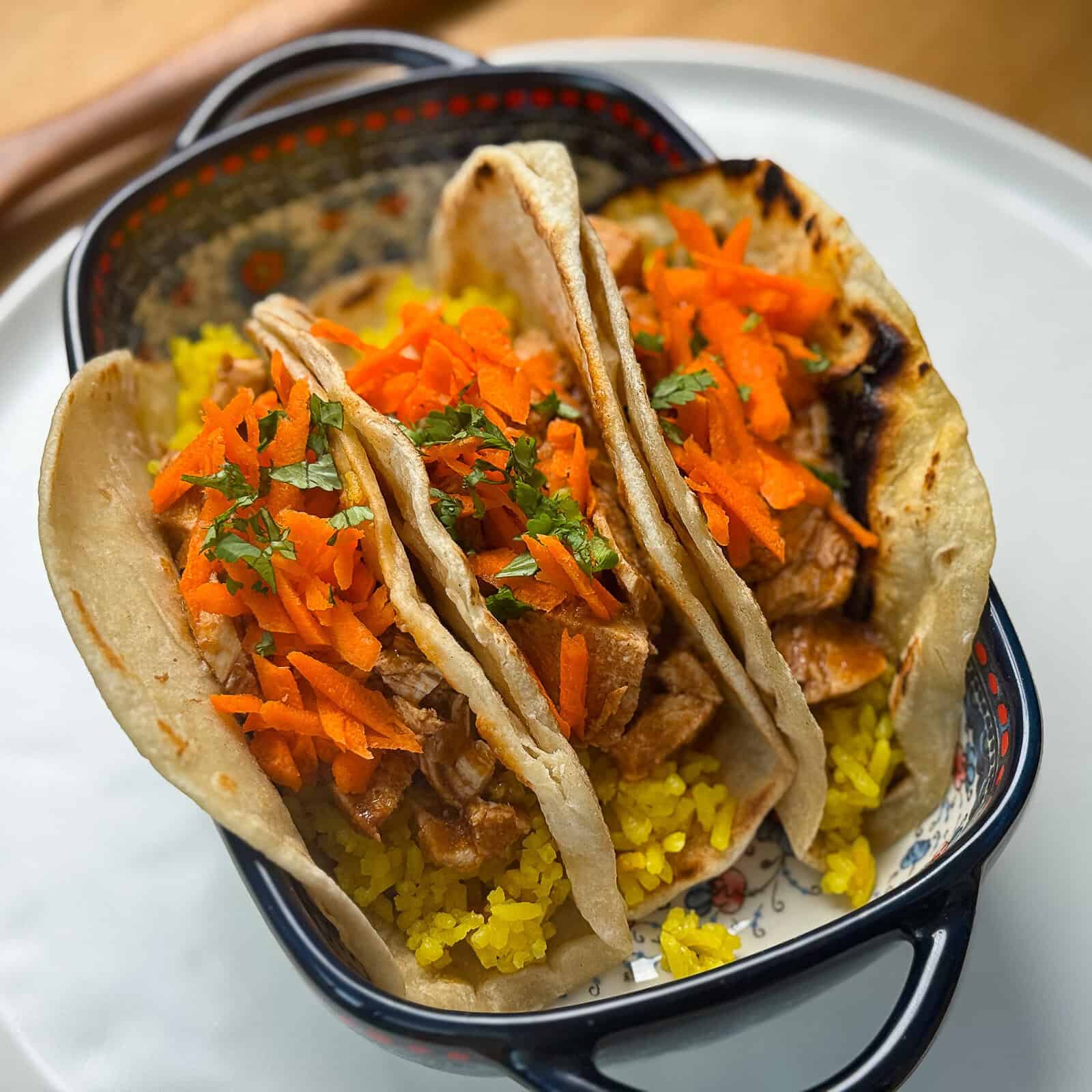 Another angle of butter chicken tacos with turmeric rice on a plate