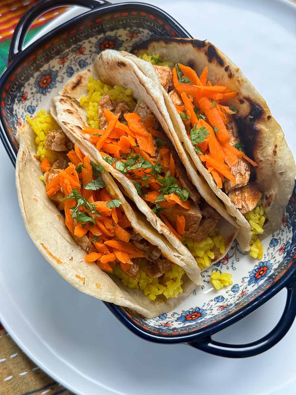 Closeup of butter chicken tacos with turmeric rice and shredded carrots on top