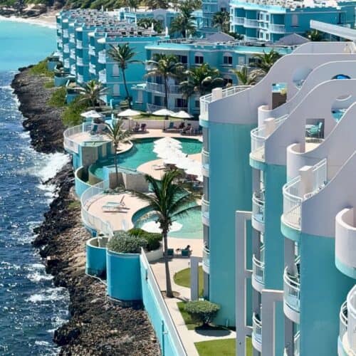 Pool and beach view at Oyster Bay Beach Resort with clear water, lounge chairs, and ocean in background