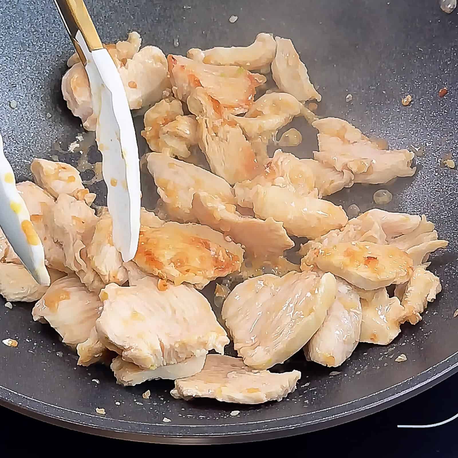 Thin sliced chicken cooking in skillet