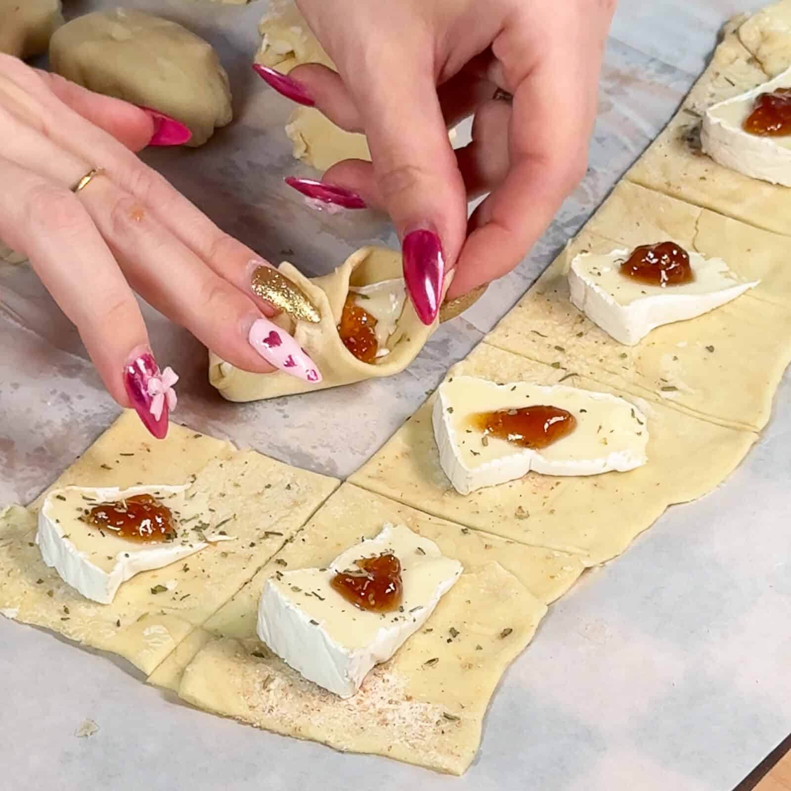 Folding corners of puff pastry over brie and fig jam
