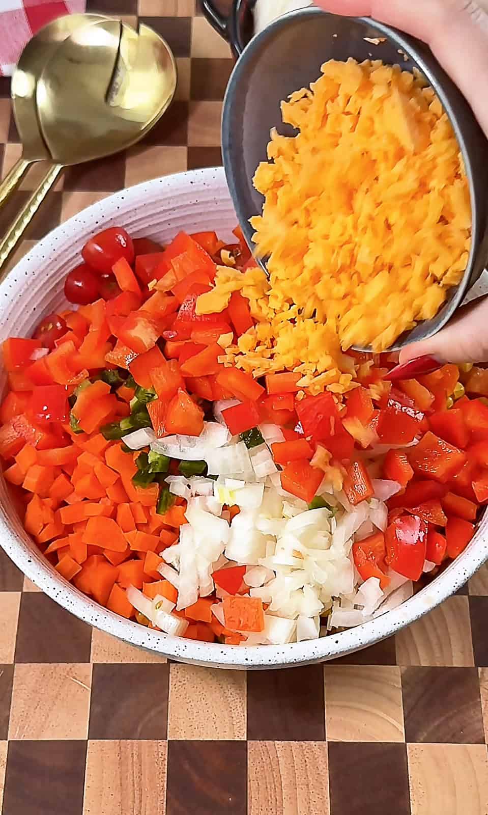 Adding shredded cheese to a bowl of Make-Ahead Corn Salsa Dip