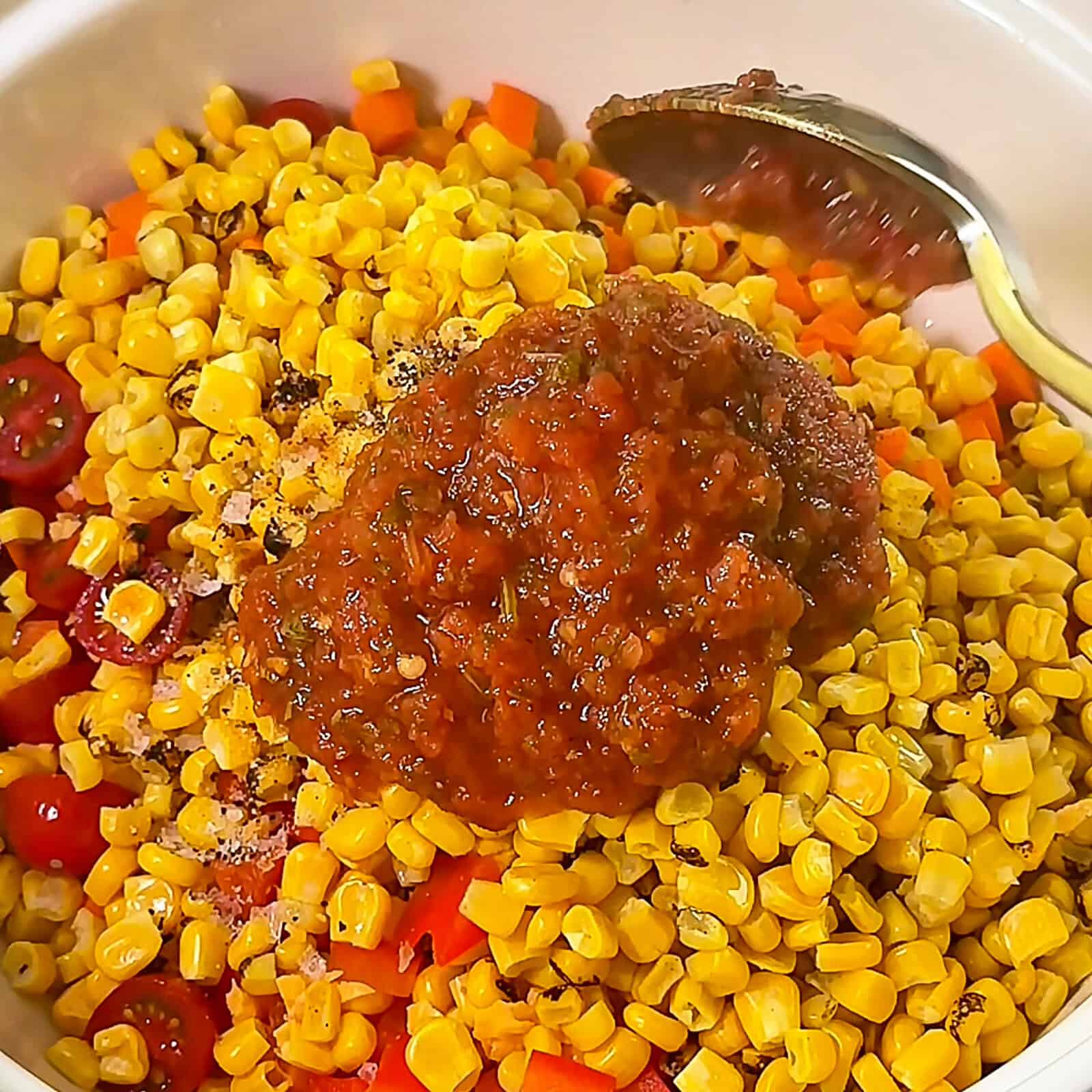 Pouring salsa into a bowl of Corn Salsa Dip