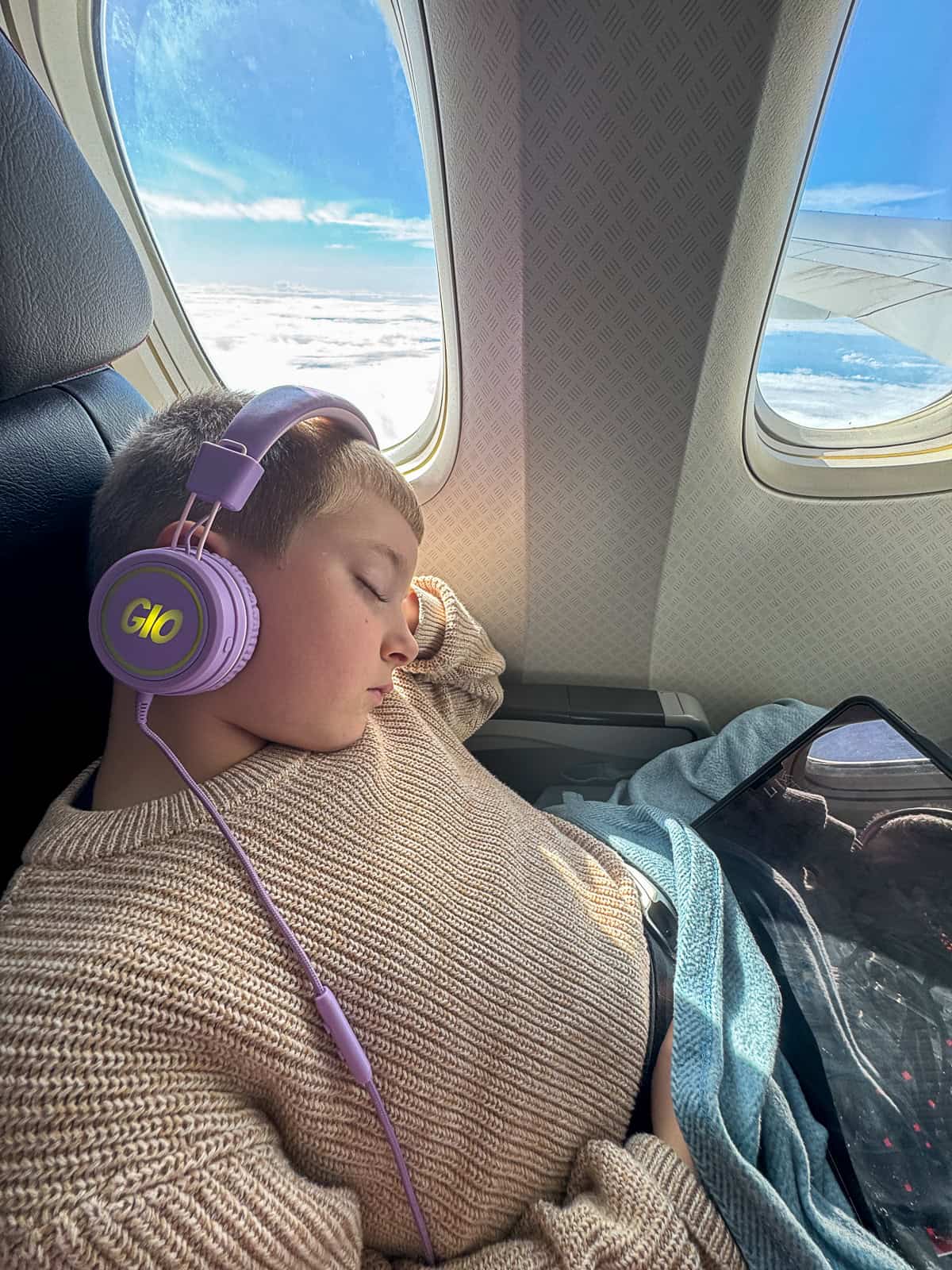 Child asleep in airplane seat during family trip