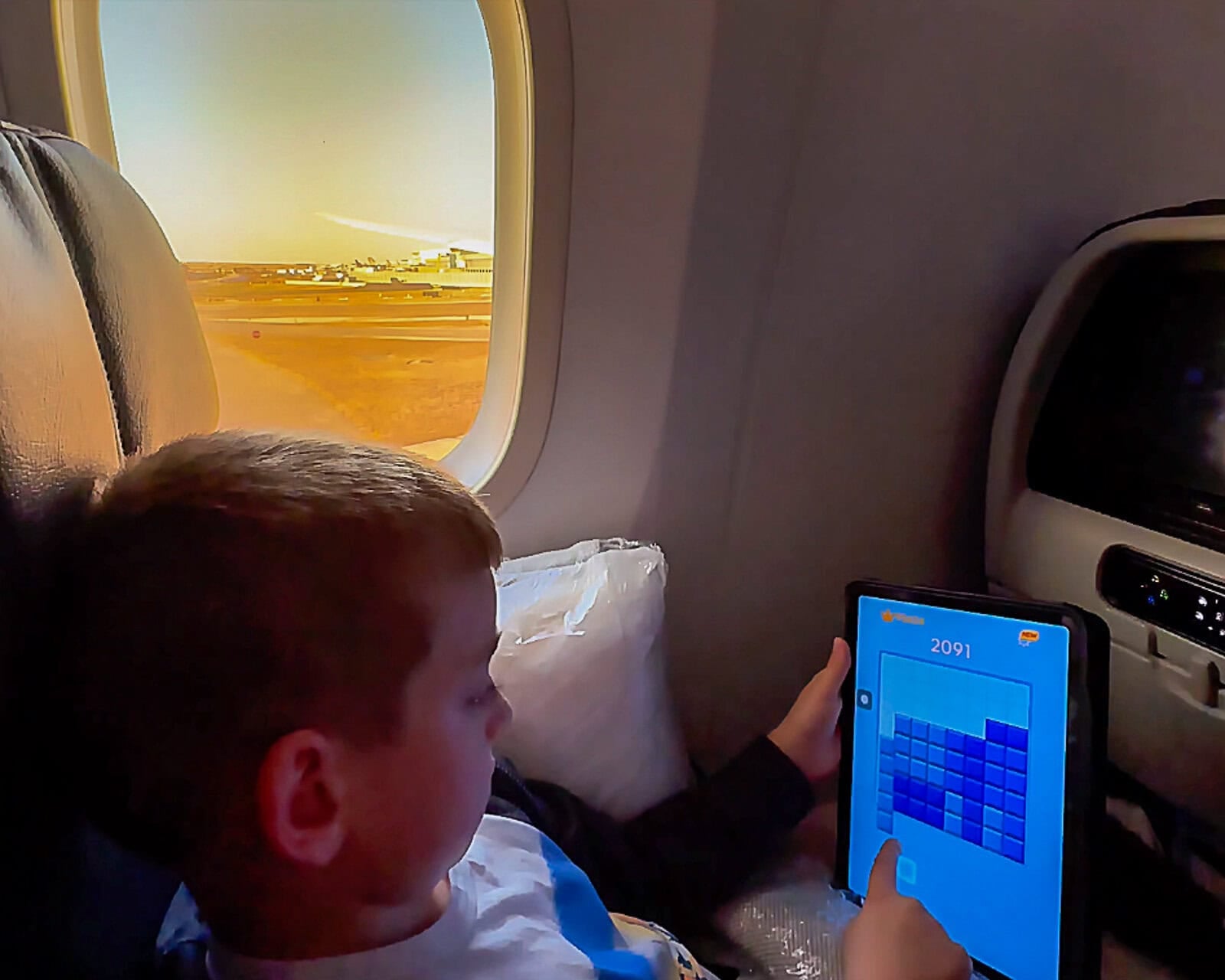 Child using iPad to stay entertained on plane