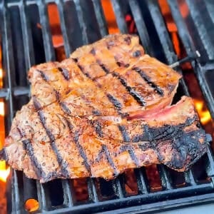 Chuck steak grilling over open flame