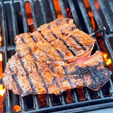 Chuck steak grilling over open flame