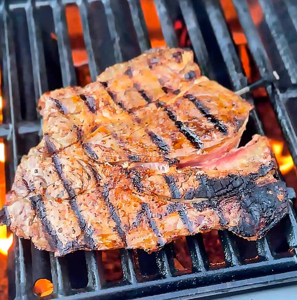 Chuck steak grilling over open flame