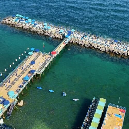 View of Marina Piccola from Marameo beach club in Sorrento, Italy with umbrellas and lounge chairs